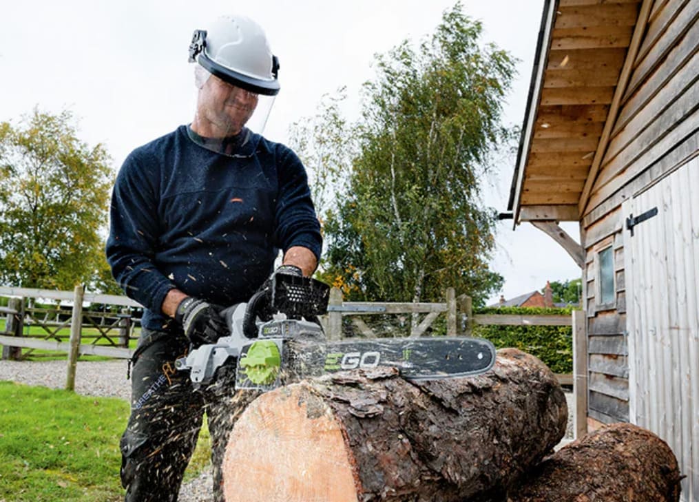 Mann schneidet Baumstamm mit EGO Kettensäge